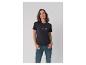 Frau in schwarzem T-Shirt mit Schriftzug und Jeans, Hände in den Taschen.