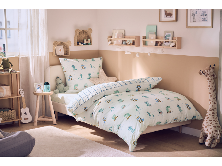 Gemütliches Kinderzimmer mit einem Bett mit Dinosaurier-Bettwäsche und verspielter Deko.