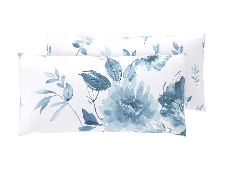 Zwei weiße Kissen mit blauem Aquarell-Blumenmuster.