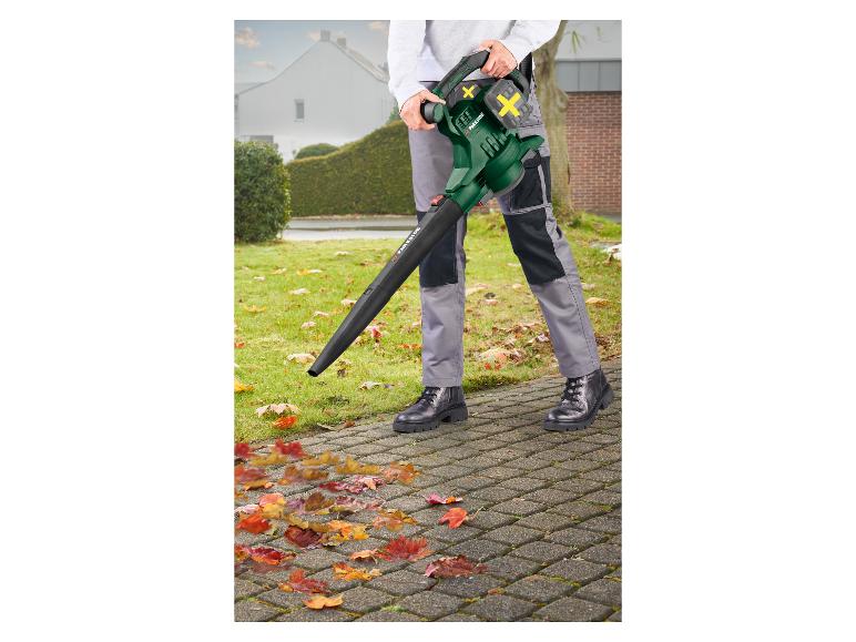Person benutzt einen Laubbläser, um Herbstlaub von einem gepflasterten Weg zu entfernen.