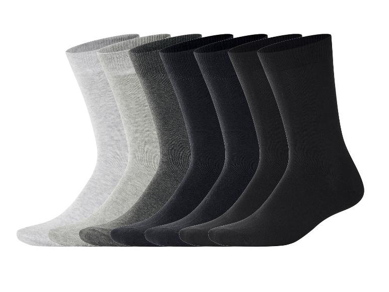 Sieben Paar Herrensocken in Grau- und Schwarztönen, in einer Reihe angeordnet.