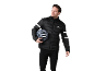 Mann in schwarzer Fahrradjacke und Leggings, hält einen grauen Fahrradhelm.