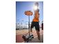 Junger Mann im orangefarbenen Basketballtrikot wirft einen Korb in der Sonne.