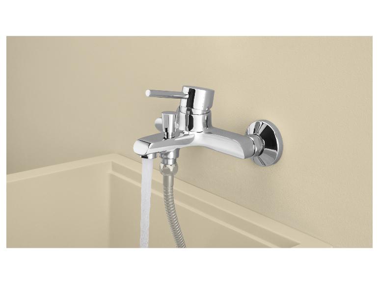 Verchromte Badewannenarmatur mit Wasser, das in eine helle Badewanne läuft.