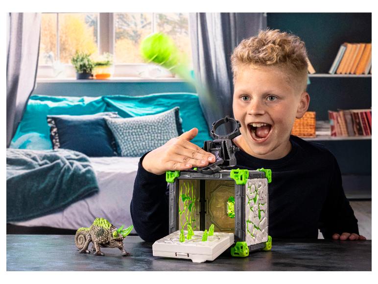 Junge spielt mit einem Spielset mit Werfer und Echsenfigur.