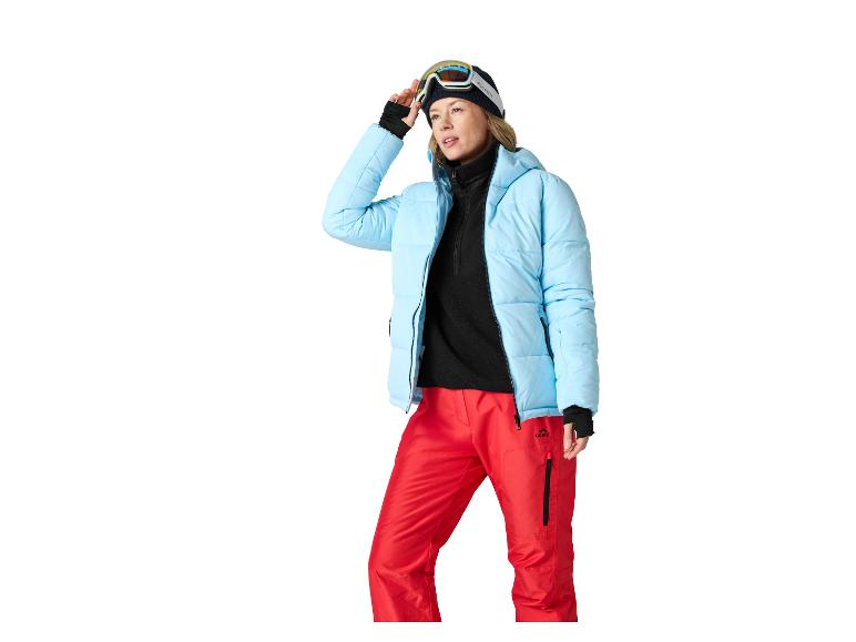 Frau in blauer Skijacke, roter Hose und Skibrille.