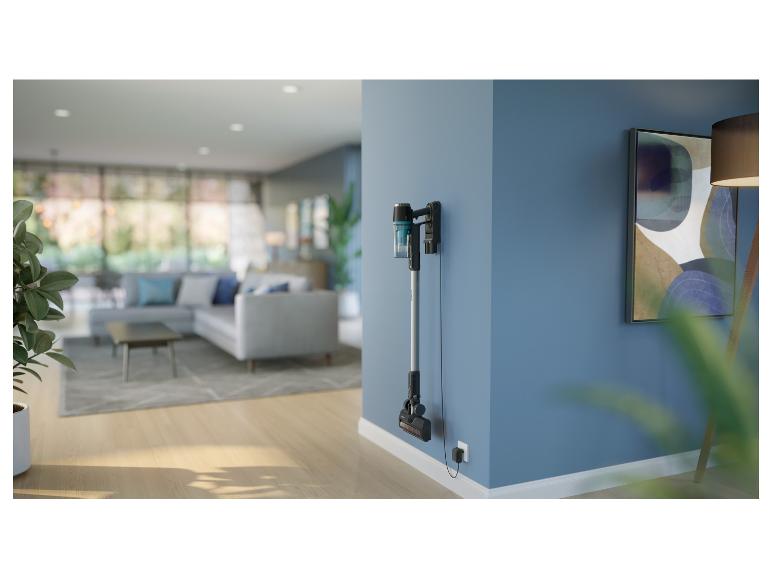 Kabelloser Staubsauger an einer blauen Wand in einem modernen Wohnzimmer.