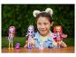 Lächelndes Mädchen mit Enchantimals-Puppen und Tierfiguren auf einem Tisch.