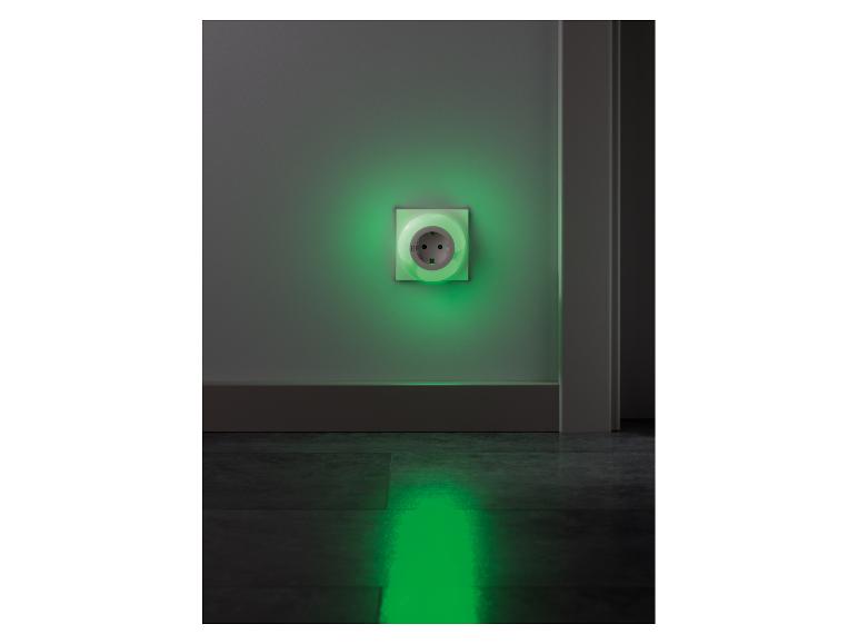 Steckdose mit integriertem grünem Nachtlicht, das Wand und Boden beleuchtet.