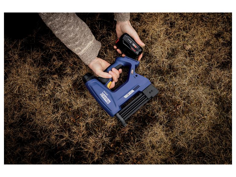 Person setzt Akku in blauen LIVARNO® 18V Akkutacker BTX606 auf trockenem Gras ein.