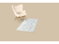Beiger Sessel mit hellblauem Teppich auf beigem Hintergrund.