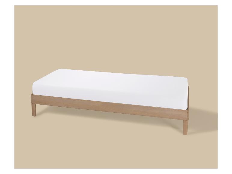 Einzelbett aus Holz mit weißer Matratze auf beigem Hintergrund.