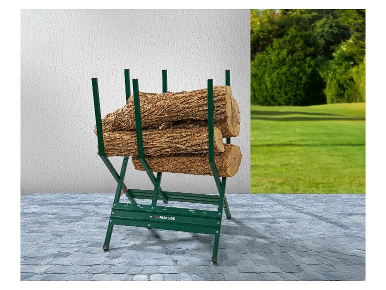 Grüner Sägebock mit drei Holzstämmen auf einem gepflasterten Hof mit grünem Rasen im Hintergrund.