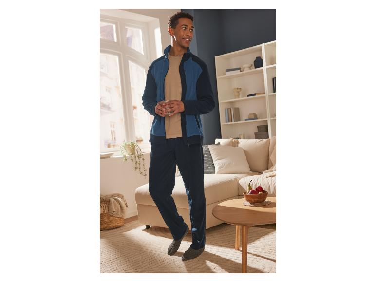 Mann in einem blauen Trainingsanzug in einem Haus.