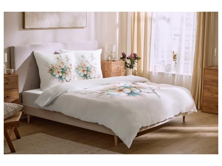 Schlafzimmer mit Doppelbett, weißer Bettwäsche mit Blumenmuster und Nachttischen aus Holz.