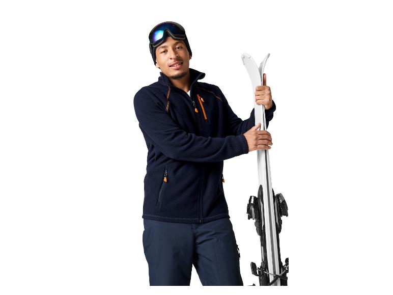 Ein Mann in Skiausrüstung hält Skier.