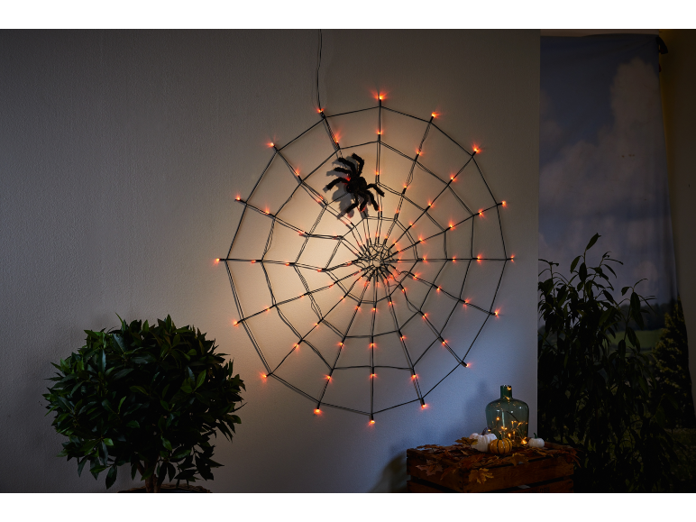 Leuchtendes Halloween-Spinnennetz mit Spinne, Kürbissen und Herbstdekorationen.