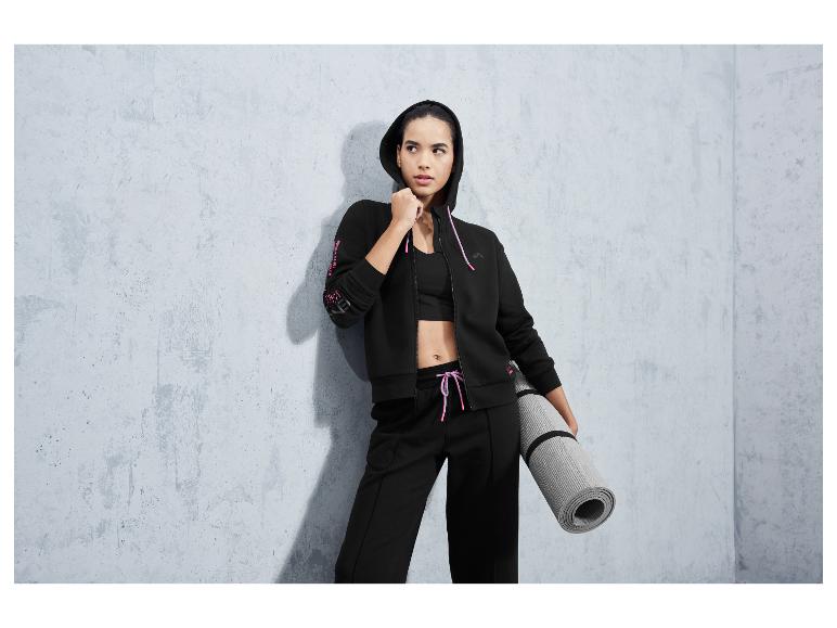 Eine Frau in schwarzer Sportbekleidung mit einer Yogamatte.