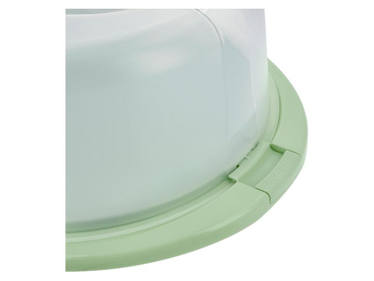 Nahaufnahme eines hellgrünen Tortenbehälters mit transparentem Kuppeldeckel.