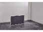 Zusammengeklappter Campingtisch in einem leeren Raum mit dunklem Boden.