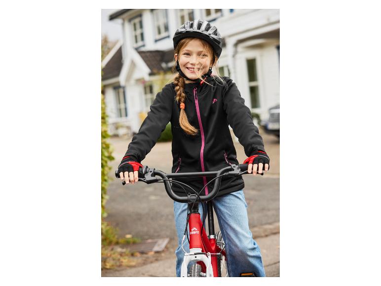 Lächelndes Mädchen mit Fahrradhelm und Jacke auf einem roten Fahrrad.