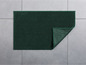 Eine dunkelgrüne Badematte mit einer Textur aus kleinen Noppen.