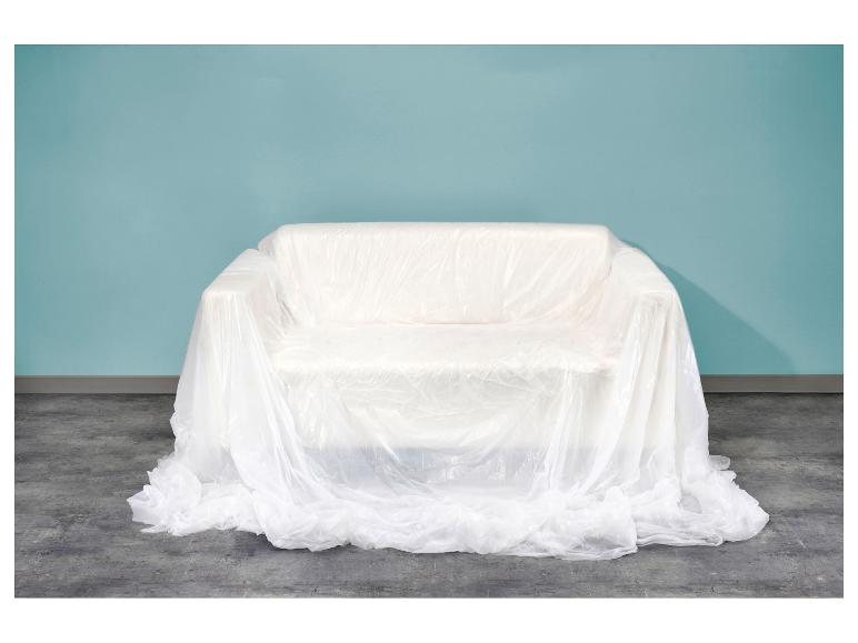 Weißes Sofa mit Plastikfolie bedeckt vor einer blauen Wand und Betonboden.