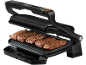 Offener Elektrogrill mit vier gegrillten Rindersteaks und einer Auffangschale.
