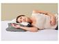 Frau schläft auf der Seite auf einem Bett mit einem grau-weißen ergonomischen Kissen.