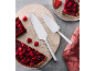 Zwei Tortenheber auf einer Marmorplatte mit Himbeertörtchen, ein Törtchen auf einem Teller mit Erdbeeren.