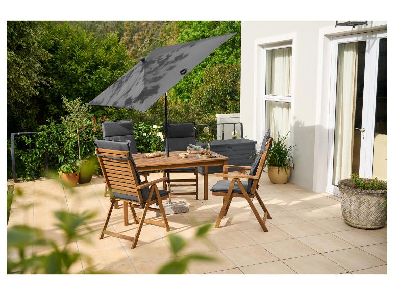 Essbereich im Freien mit Holztisch, Stühlen mit grauen Kissen und großem Sonnenschirm auf einer Terrasse.