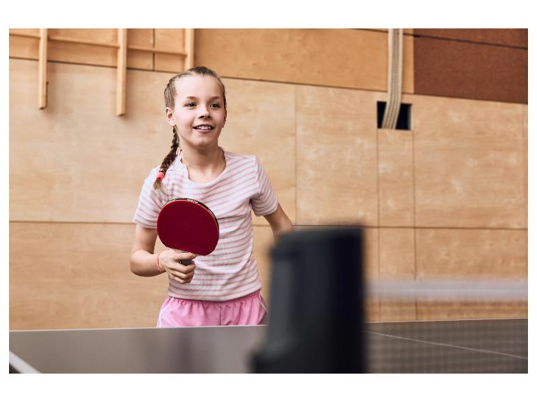 Mädchen spielt Tischtennis, hält einen roten Schläger.