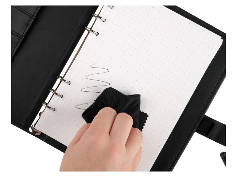 Ein schwarzer Ringbuchblock wird mit einem Tuch gereinigt.