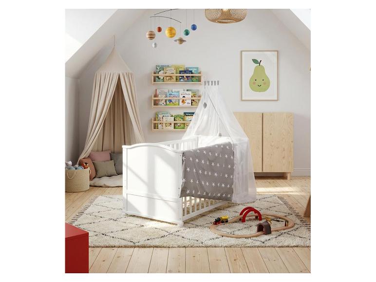Kinderzimmer mit weißem Babybett, Himmelbett, Bücherregalen und Planeten-Mobile.