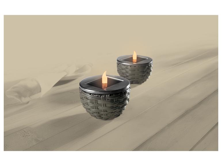 Zwei Solarleuchten mit Flammeneffekt auf einem Holztisch mit weißer Tischdecke.