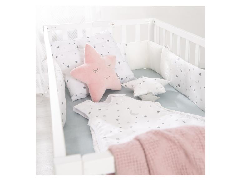 Babybett mit Sternen-Bettwäsche und einem rosa Sternenkissen.