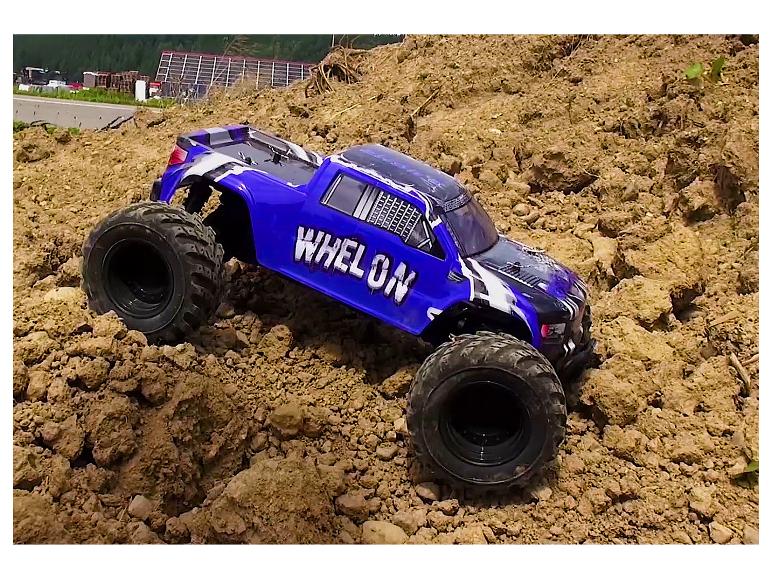 Ein blauer Whelon Monstertruck fährt einen Erdhügel hinauf.