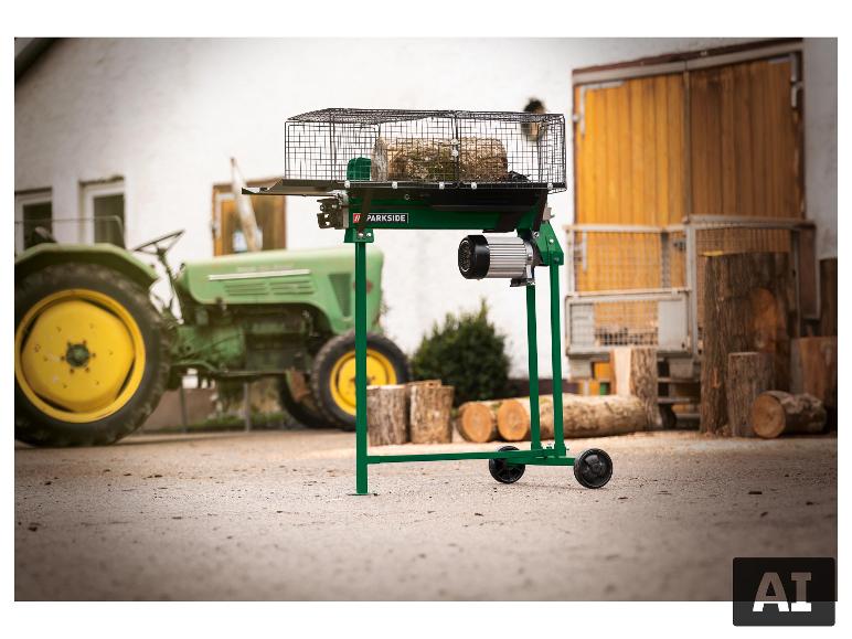 Grüner Holzspalter mit Holzscheit, auf einem Bauernhof mit Traktor im Hintergrund.