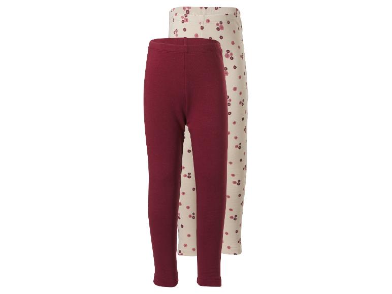 Zwei Baby-Leggings: eine einfarbige bordeauxrote und eine cremefarbene mit Blumenmuster.