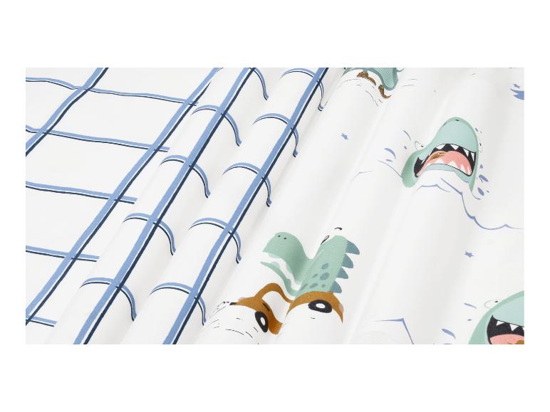 Weißer Stoff mit blauem Karomuster und Cartoon-Dinosauriern.