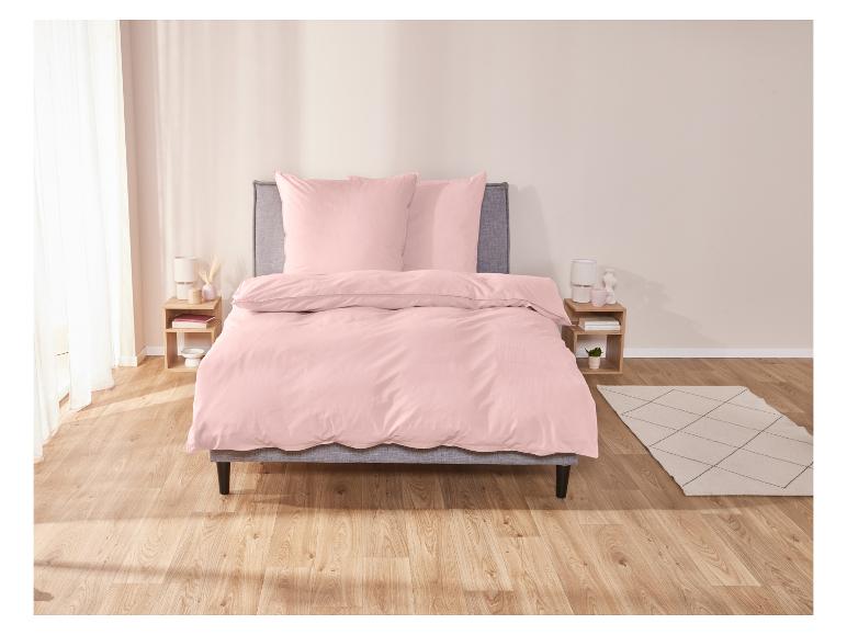 Ein rosafarbener Bettbezug auf einem Bett mit zwei Kissen.