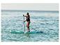 Frau paddelt auf einem Stand-Up-Paddle-Board im Meer, mit Schwimmweste.