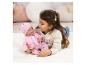 Mädchen spielt mit einer rosa gekleideten Babypuppe, liegend auf einem weißen Teppich.