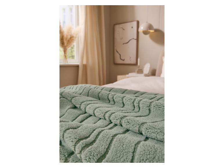 Weiche grüne LIVARNO home Kuscheldecke auf einem Bett.