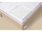Matratze mit abnehmbarem Bezug und Schaumstofftopper auf einem Holzbett.