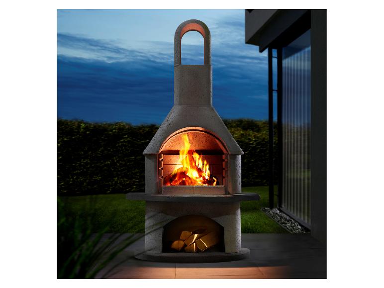 Betongrill mit brennendem Holz, draußen auf einer Terrasse in der Dämmerung.