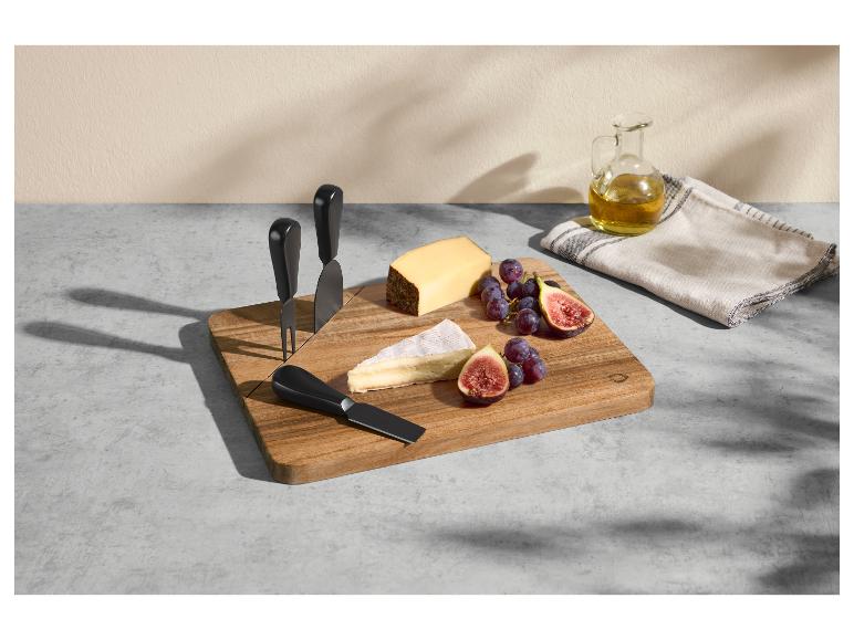 Käsebrett mit Messern, Käse, Trauben und Feigen, daneben Olivenöl und ein Tuch.