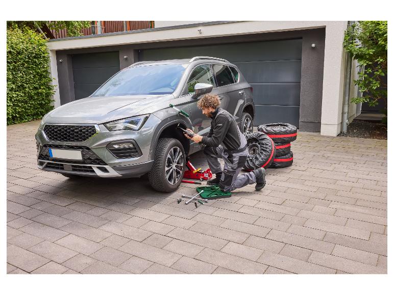 Mann wechselt Autoreifen, mit Wagenheber und Radschlüsseln.