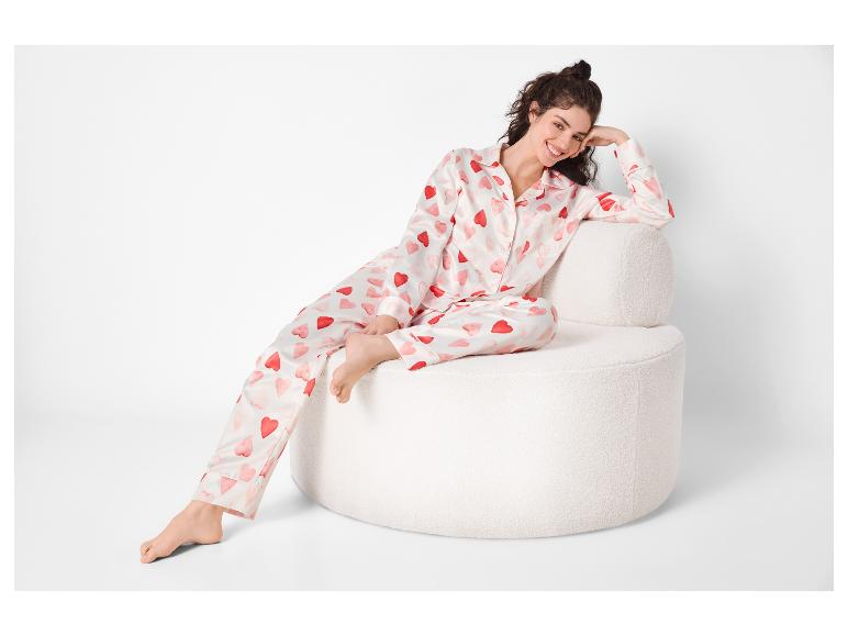 Frau in weißem Pyjama mit roten Herzen, sitzt auf einem weißen Sessel.