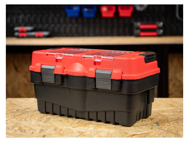 Rot-schwarzer Werkzeugkasten auf einer Holzwerkbank mit Werkstattlagerung im Hintergrund.